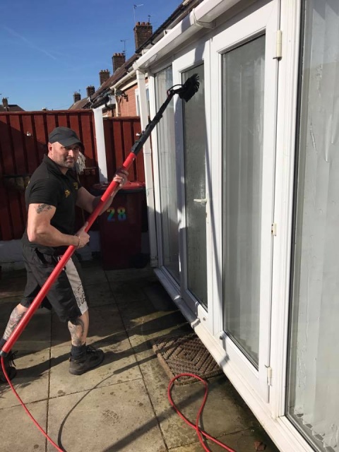 Image of worker from The Gleam Team cleaning a fascia outside.