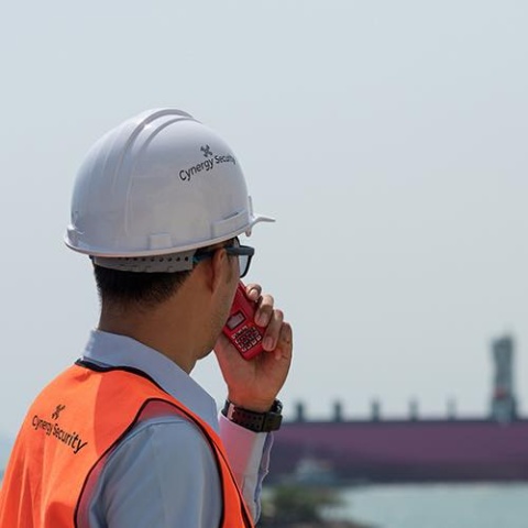 A security guard with a phone looking away from the camera