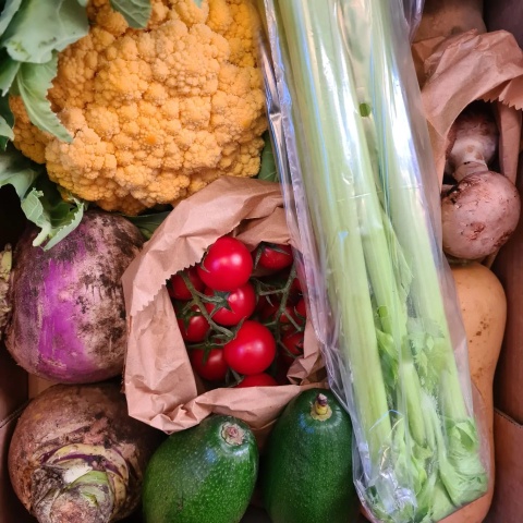 fruit and veg box, containing tomatoes, courgettes, cauliflower, celery, potatoes and squash.